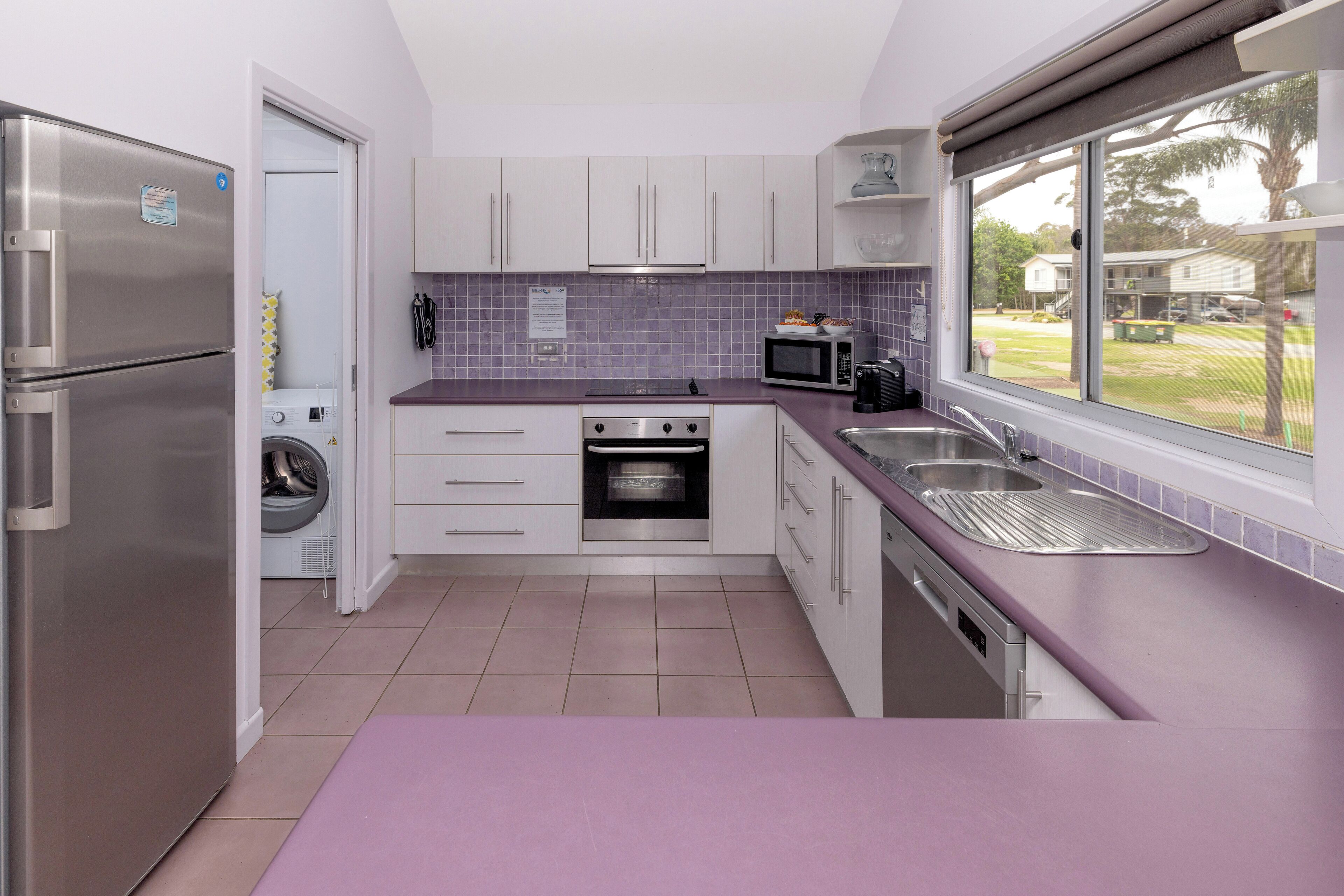 A compact kitchen with a stainless steel refrigerator, a built-in oven, a microwave, and a sink.