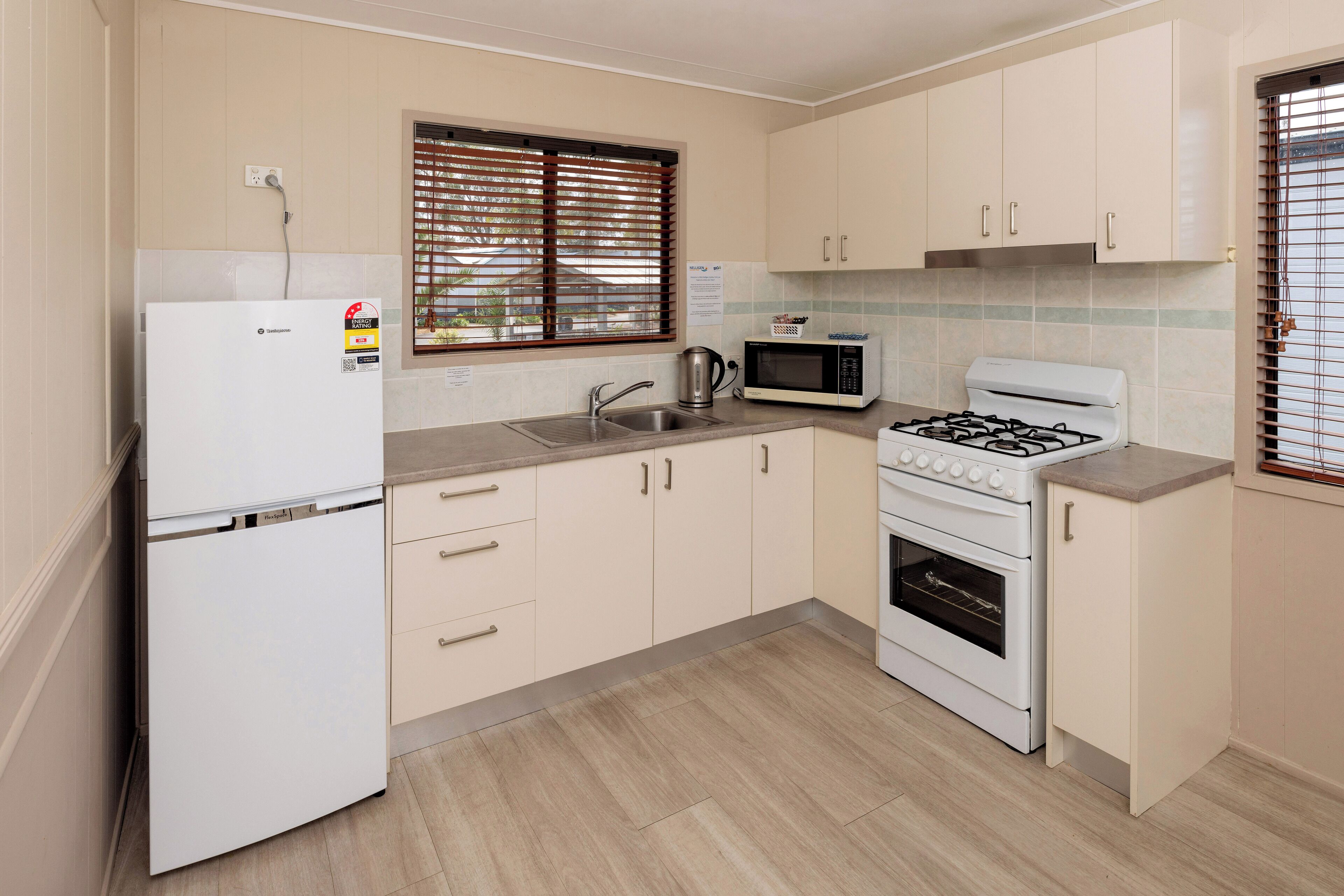 A kitchen with a refrigerator, stove, microwave, sink, and cabinets.
