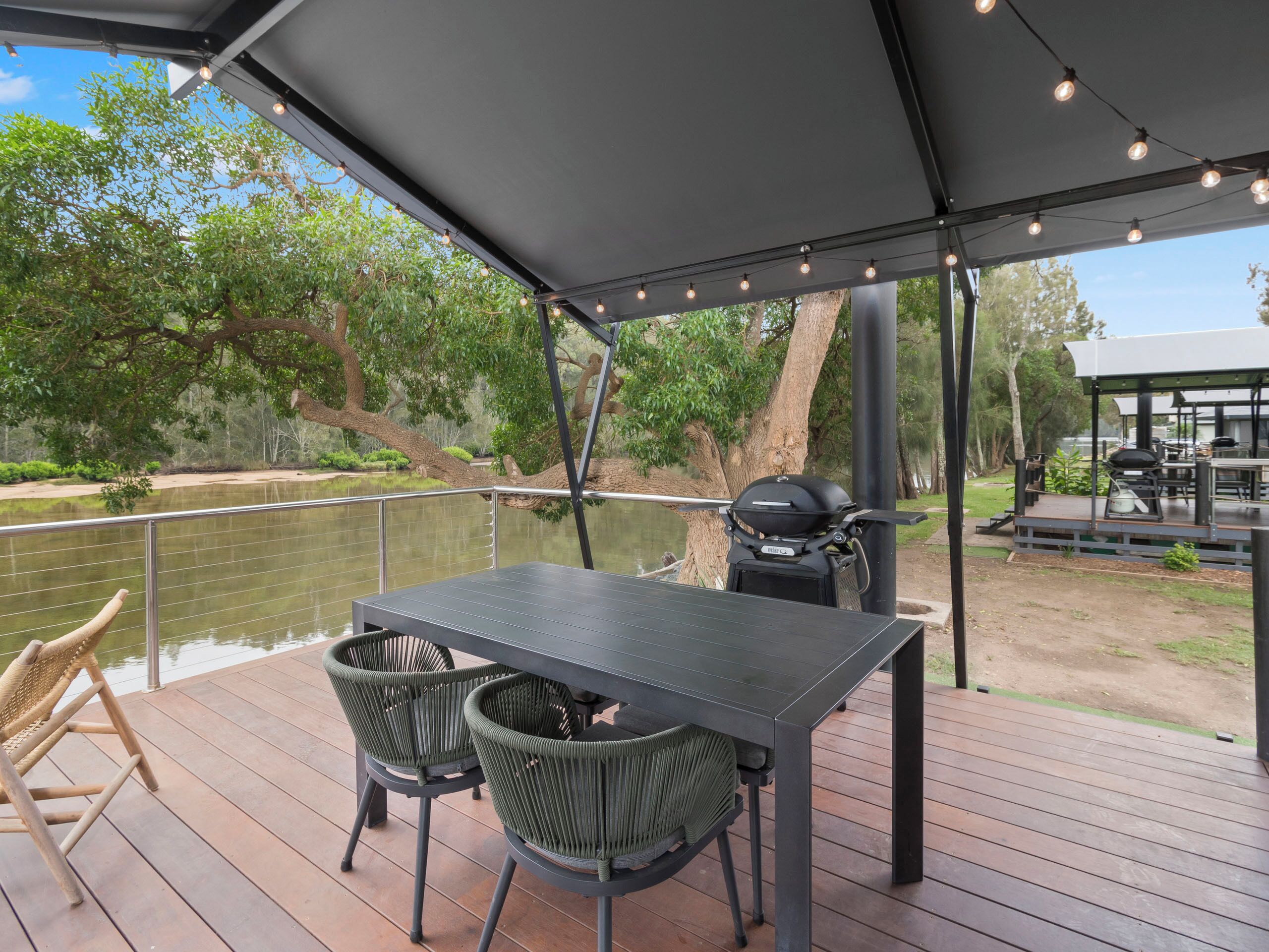 An outdoor deck with a table and chairs, a grill, and a view of a lake.