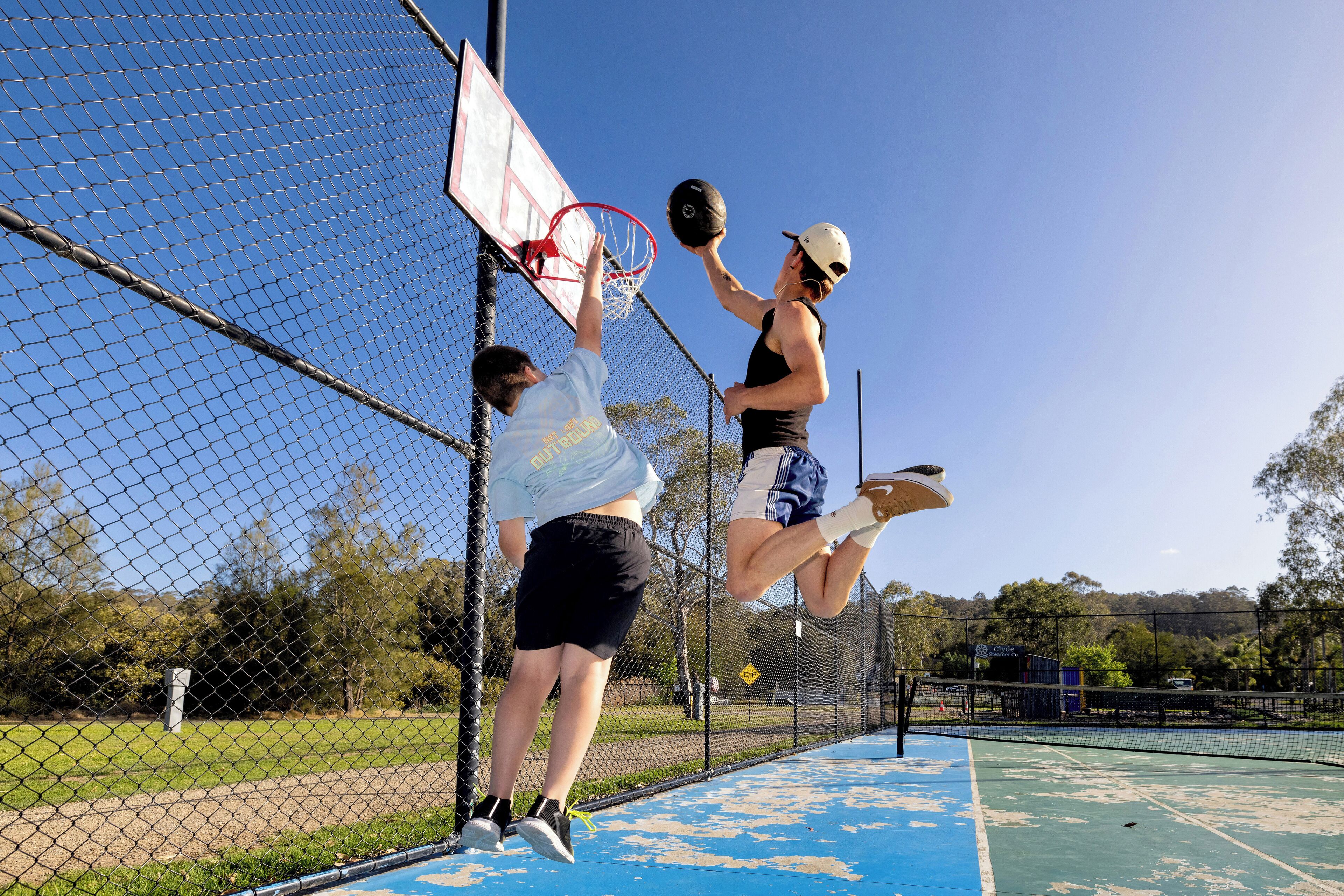 A basketball court with a chain-link fence, a basketball hoop, and a net.