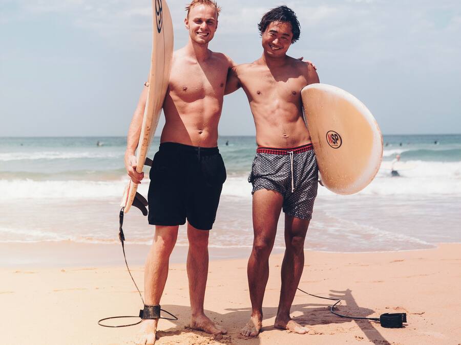 Dos personas en una playa sosteniendo tablas de surf.