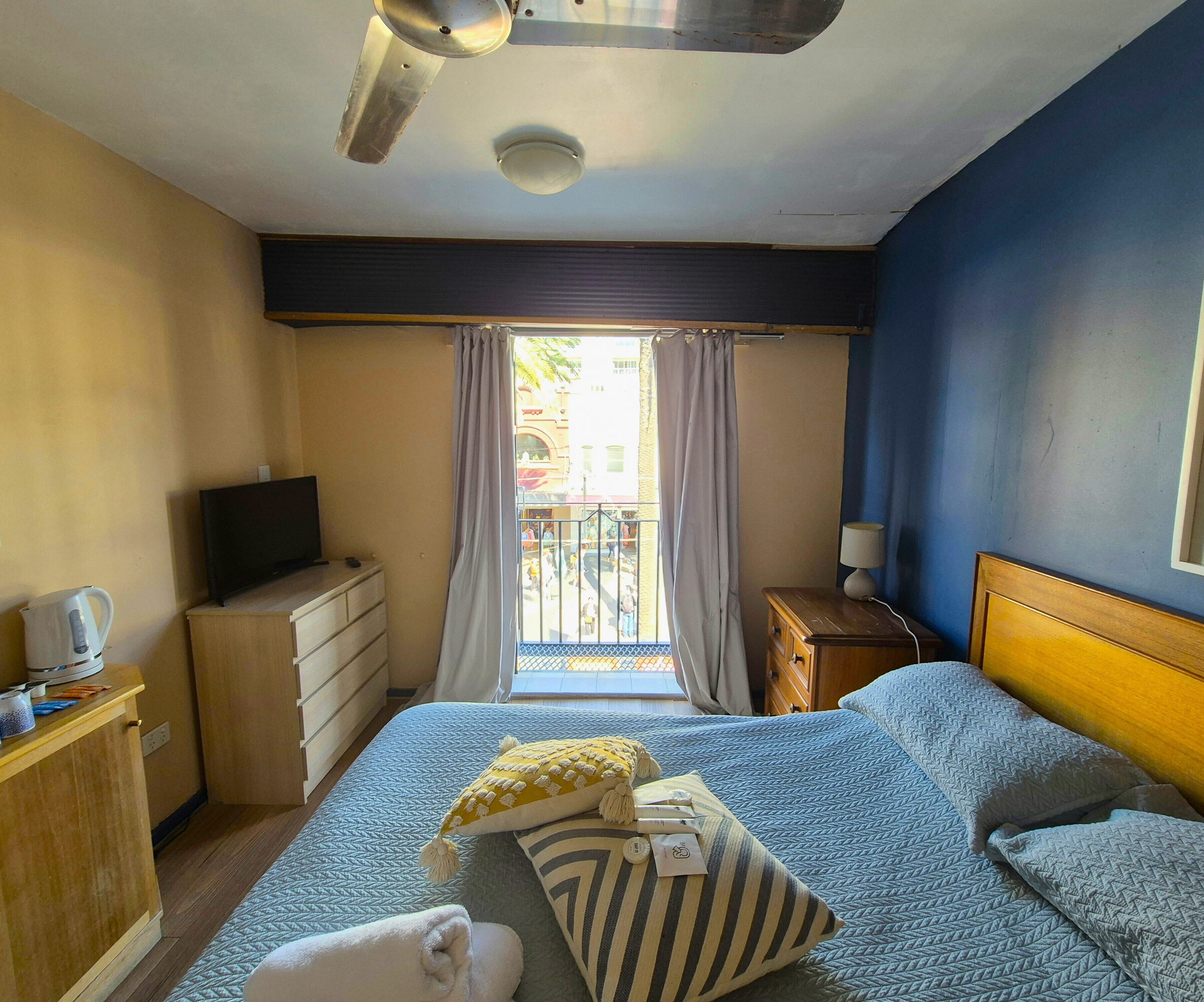 A hotel room with a bed, a television, a desk, and a window with curtains.