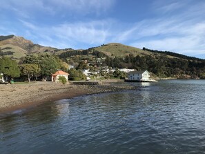Vista sobre un lago con un pequeño muelle, un edificio blanco y una construcción con techo rojo.