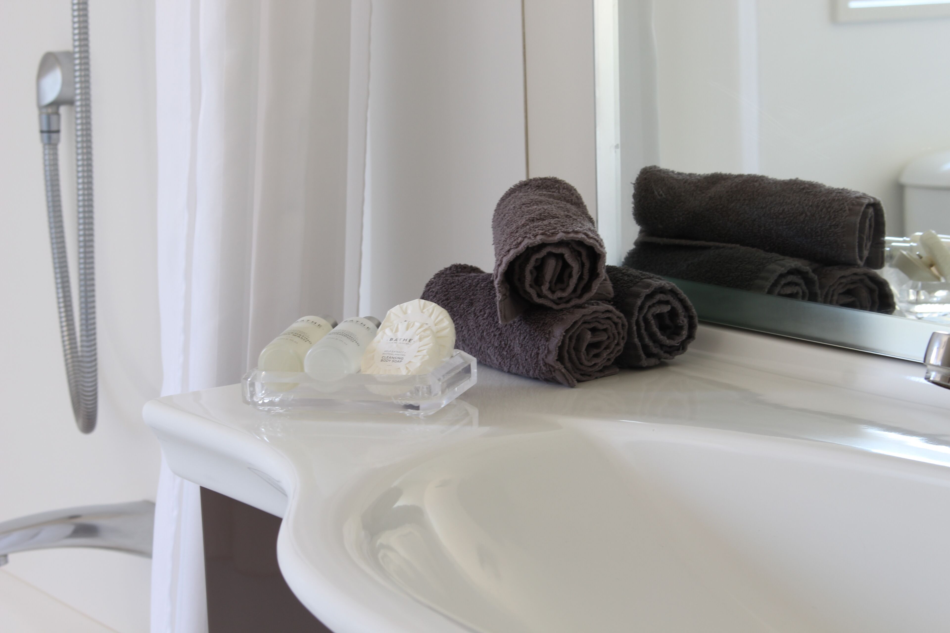 A bathroom with a white sink, a mirror, and a towel rack.
