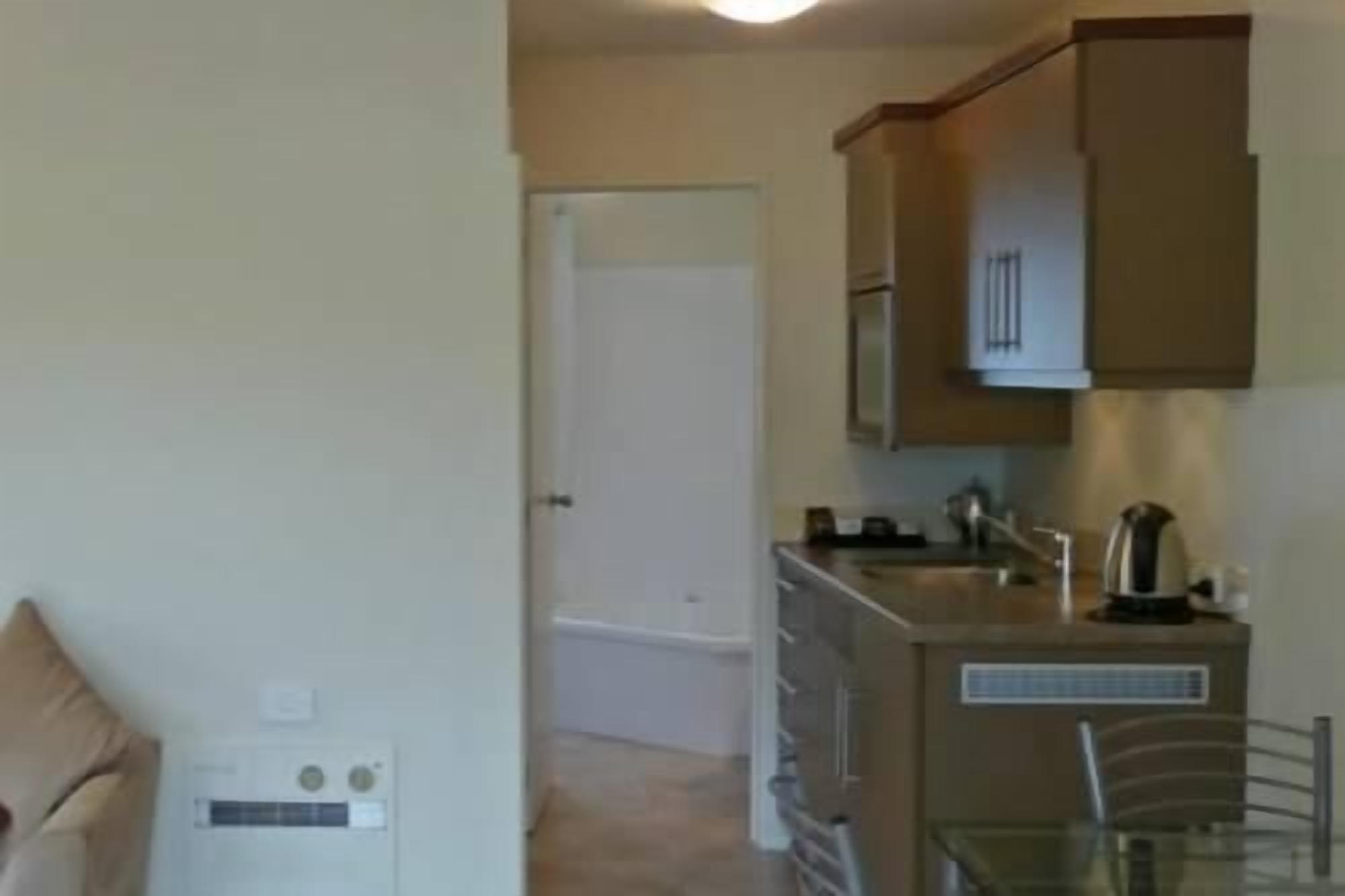 Una cocina compacta con un refrigerador, microondas y cafetera en la encimera.
