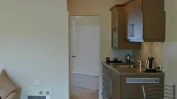 Una cocina compacta con un refrigerador, microondas y cafetera en la encimera.