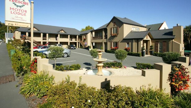 A motor lodge with multiple buildings, a parking area, and a central fountain. - Tresori Motor Lodge (Akaroa)