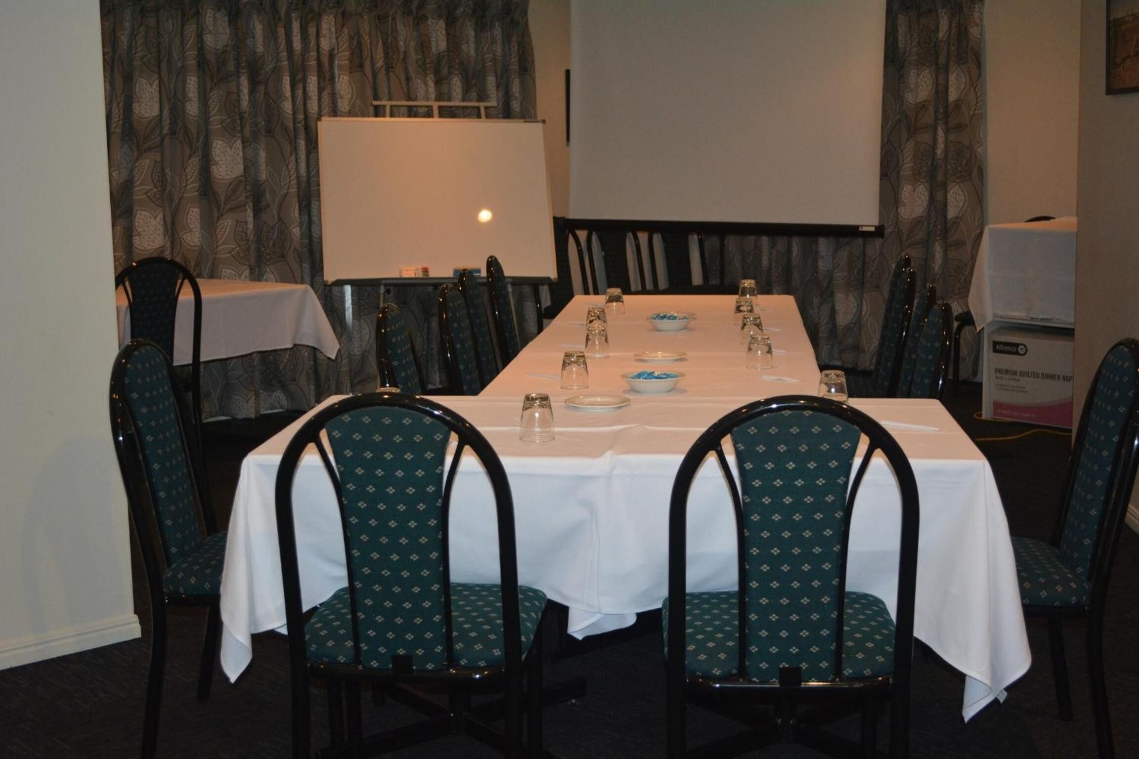 Une salle de conférence avec une longue table préparée pour une réunion, entourée de chaises.