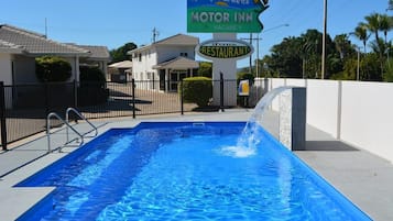En swimmingpool med et skilt for Rocky Gardens Motor Inn og Ferns Restaurant.