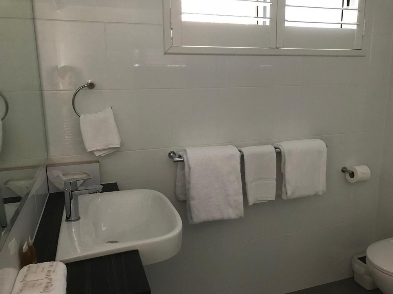 A bathroom with a sink, mirror, and three towels hanging on the wall.