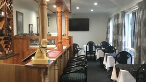 Un restaurante con barra, varias mesas y sillas.
