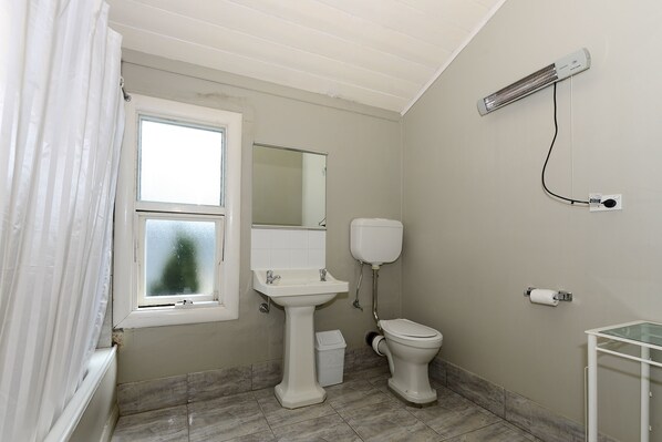 A bathroom with a window, sink, toilet, and a wall-mounted air conditioner. - Edinburgh Gallery Bed & Breakfast (Hobart)