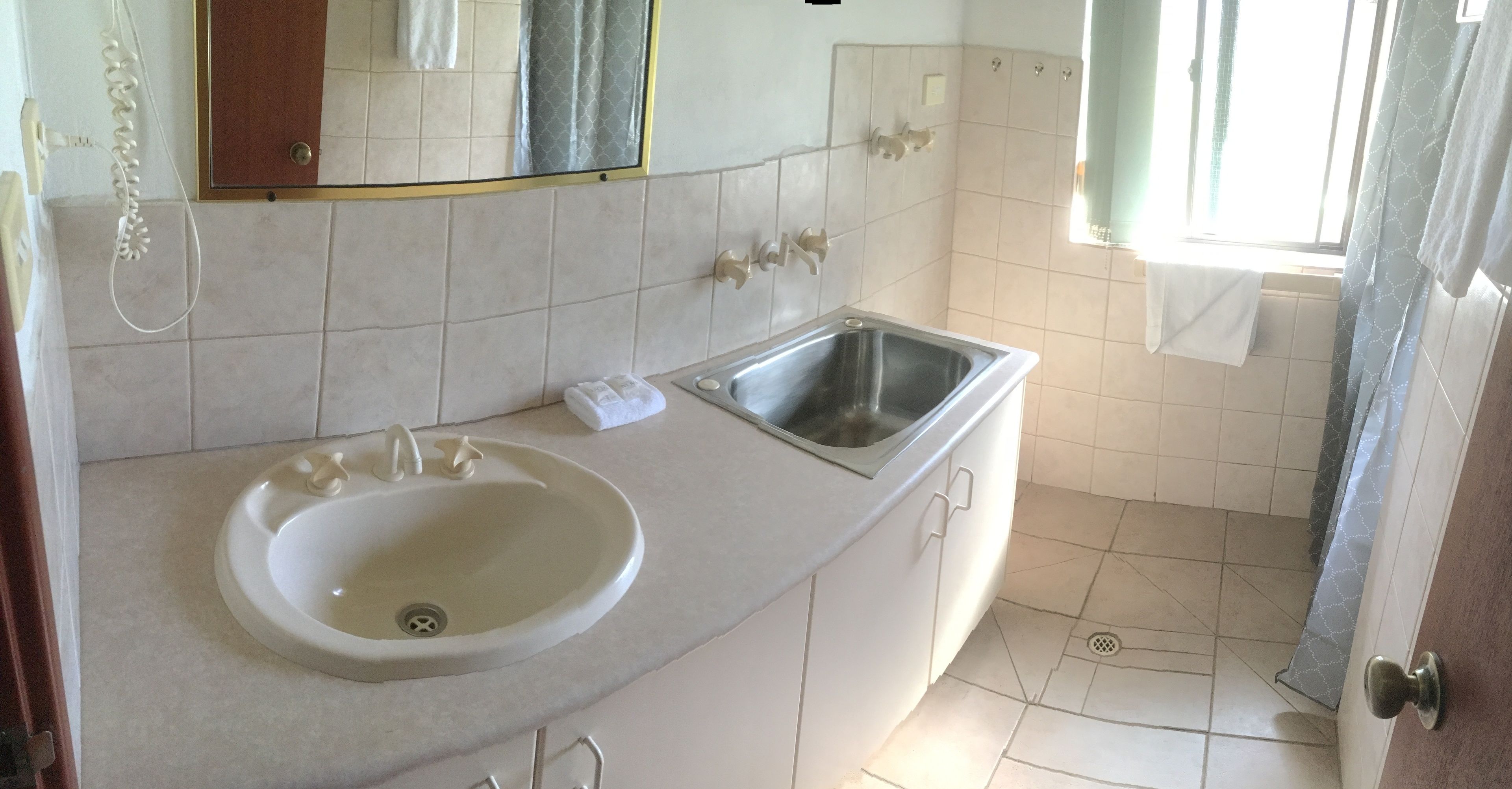 Une salle de bain avec un lavabo blanc, un miroir et un espace douche.