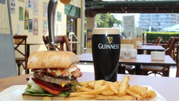Una comida con una hamburguesa, papas fritas y una cerveza Guinness sobre una mesa en un restaurante.