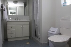 Baño con lavamanos, espejo e inodoro blancos.