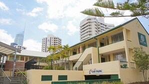 A building with a 'Car Park' sign, a staircase, and a green fence. - Darcy Arms Motel (Surfers Paradise)