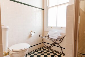 A bathroom with white subway tiles, a checkered floor, a toilet, a towel rack, and a window. - Lindsay House Guesthouse (Armidale)