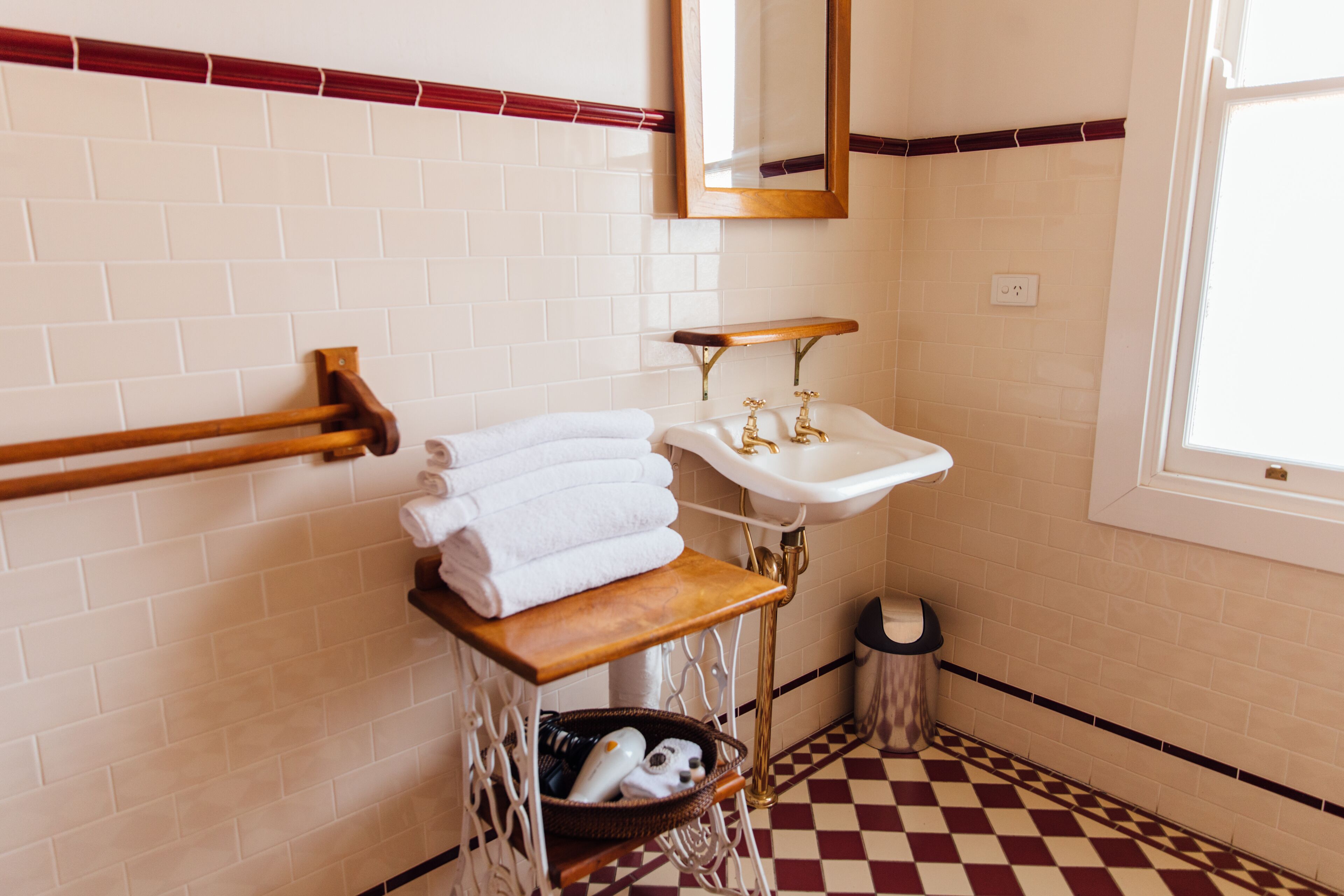 A bathroom with a white sink, a mirror, and a towel rack.