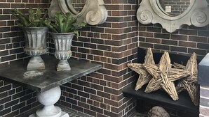 A corner with a brick wall, two ornate mirrors, a table with potted plants, and decorative starfish. - Lindsay House Guesthouse (Armidale)
