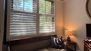 A room with a wooden bench, a lamp, and a television on a wooden stand. - Lindsay House Guesthouse (Armidale)