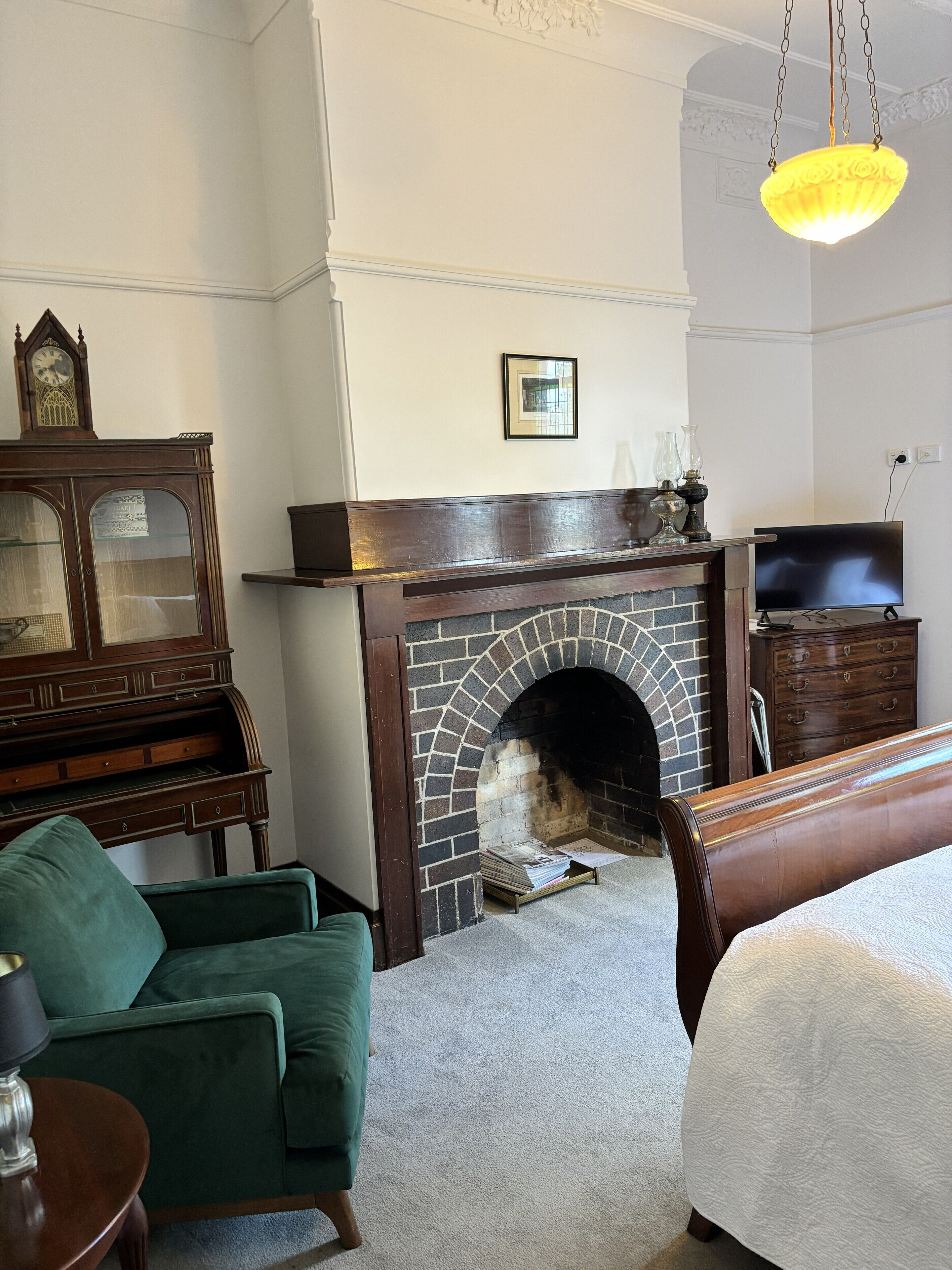 A room with a fireplace, a green sofa, a wooden cabinet, and a television.