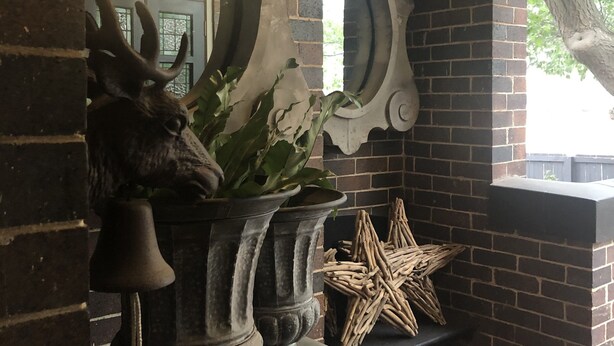 A stone archway with a decorative bell and a potted plant. - Lindsay House Guesthouse (Armidale)