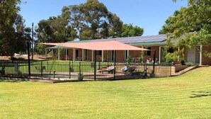 A house with a covered patio, a fenced yard, and a solar panel on the roof. - Bullanginya Lodge (Barooga)