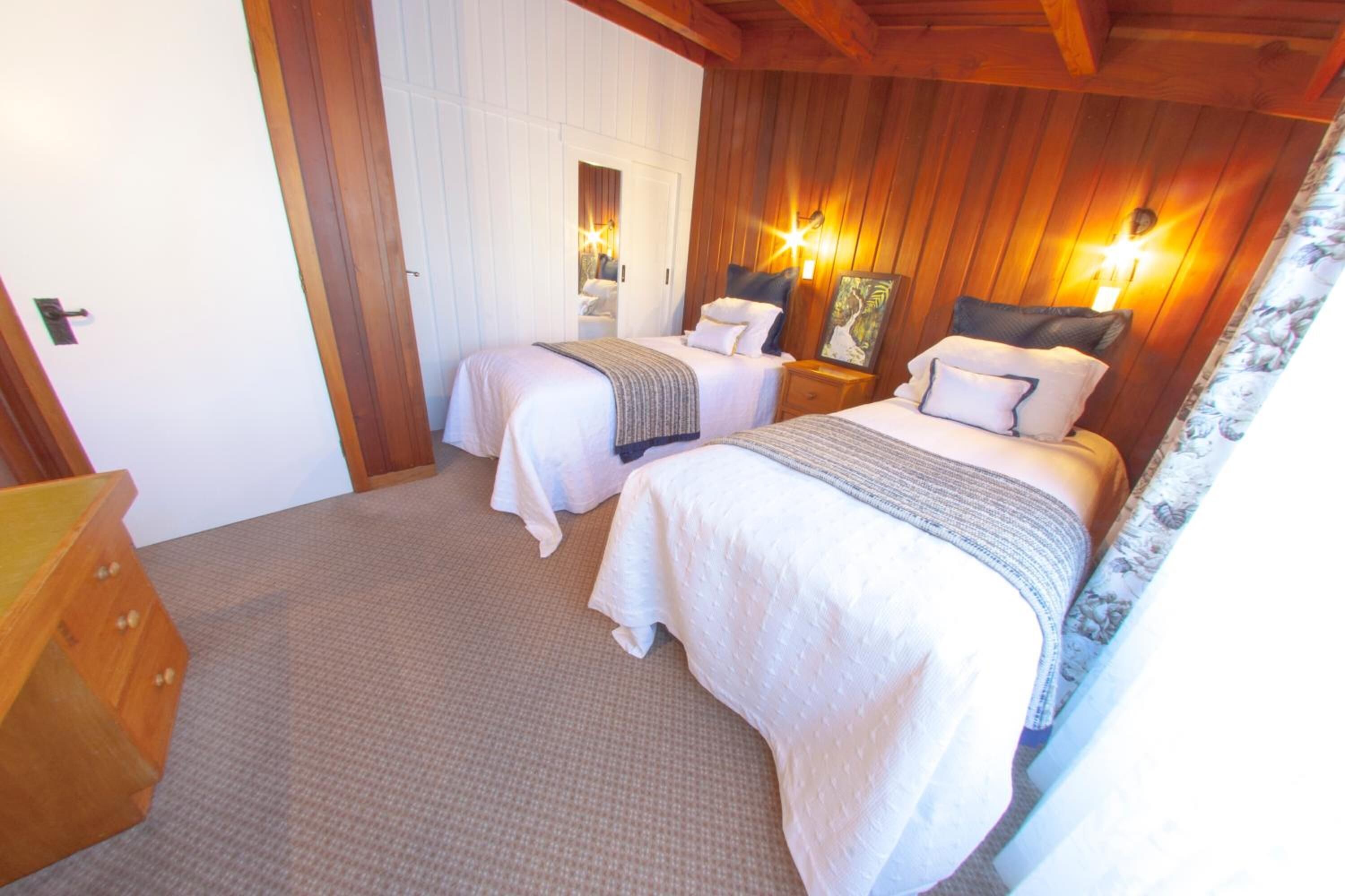 Une chambre avec deux lits, des murs en bois et des lampes de chevet.