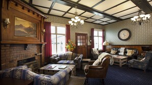 A traditional room with a fireplace, multiple seating areas, a clock, and a chandelier. - Okoroire Hot Springs Hotel (Tapapa)