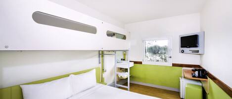 Una habitación de hotel compacta con literas, un baño pequeño, televisión y ventana con vistas.