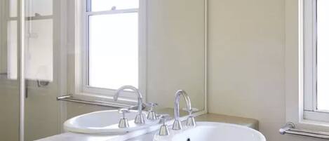 Une salle de bain avec deux lavabos, un miroir et une fenêtre.