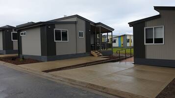 A row of modern, single-story mobile homes with a covered porch and a small set of stairs leading to the entrance.