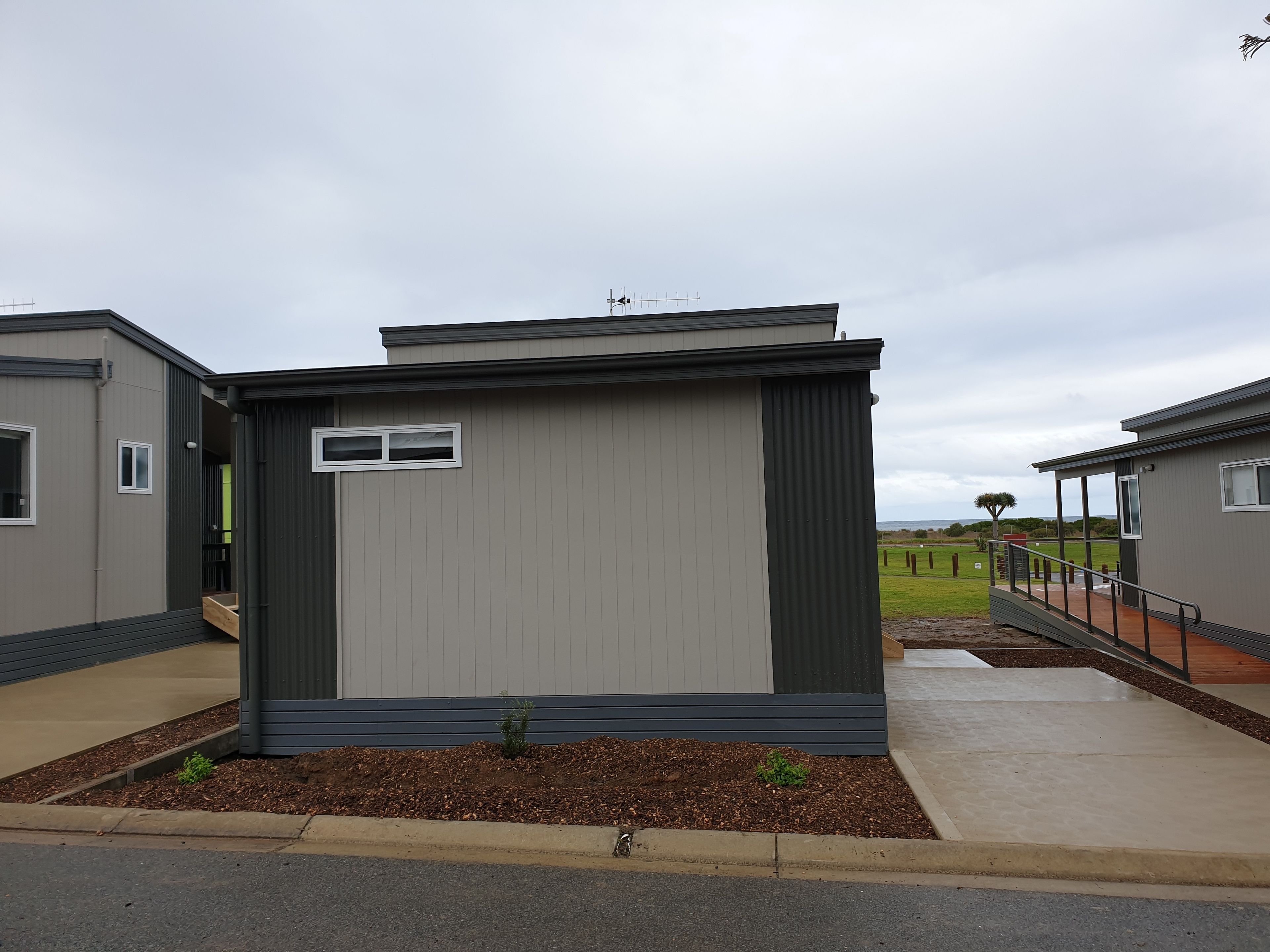A modern, single-story mobile home with a flat roof, a small porch, and a window.