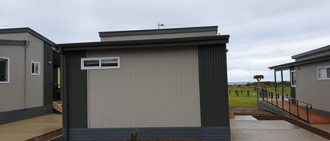 A modern, single-story mobile home with a flat roof, a small porch, and a window.