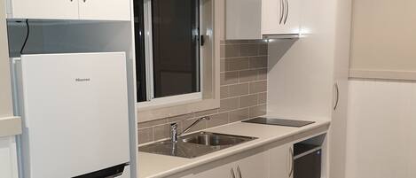 A modern kitchen with white cabinetry, a stainless steel sink, and a built-in oven.