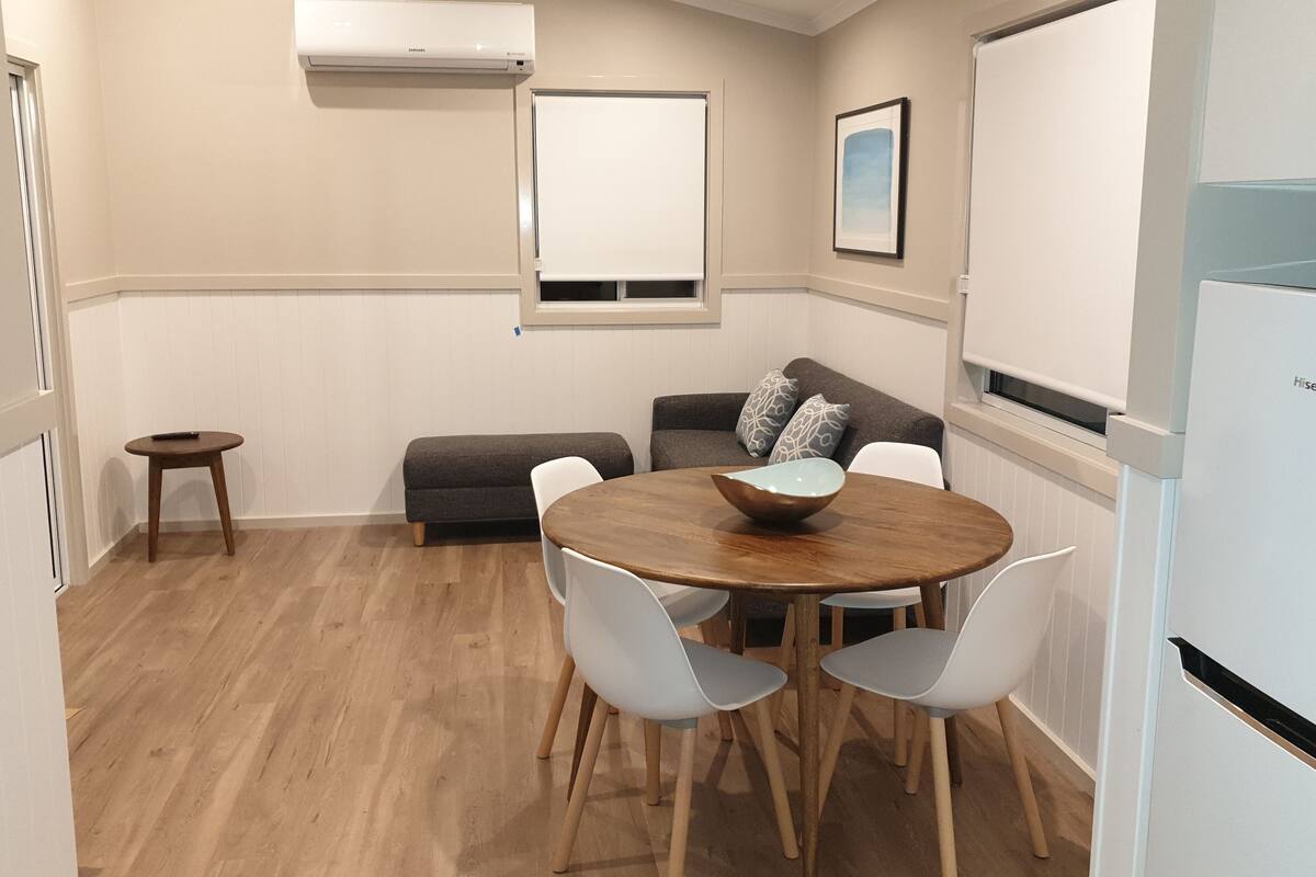 A compact living space with a dining area, a sofa, a small table, and a refrigerator.