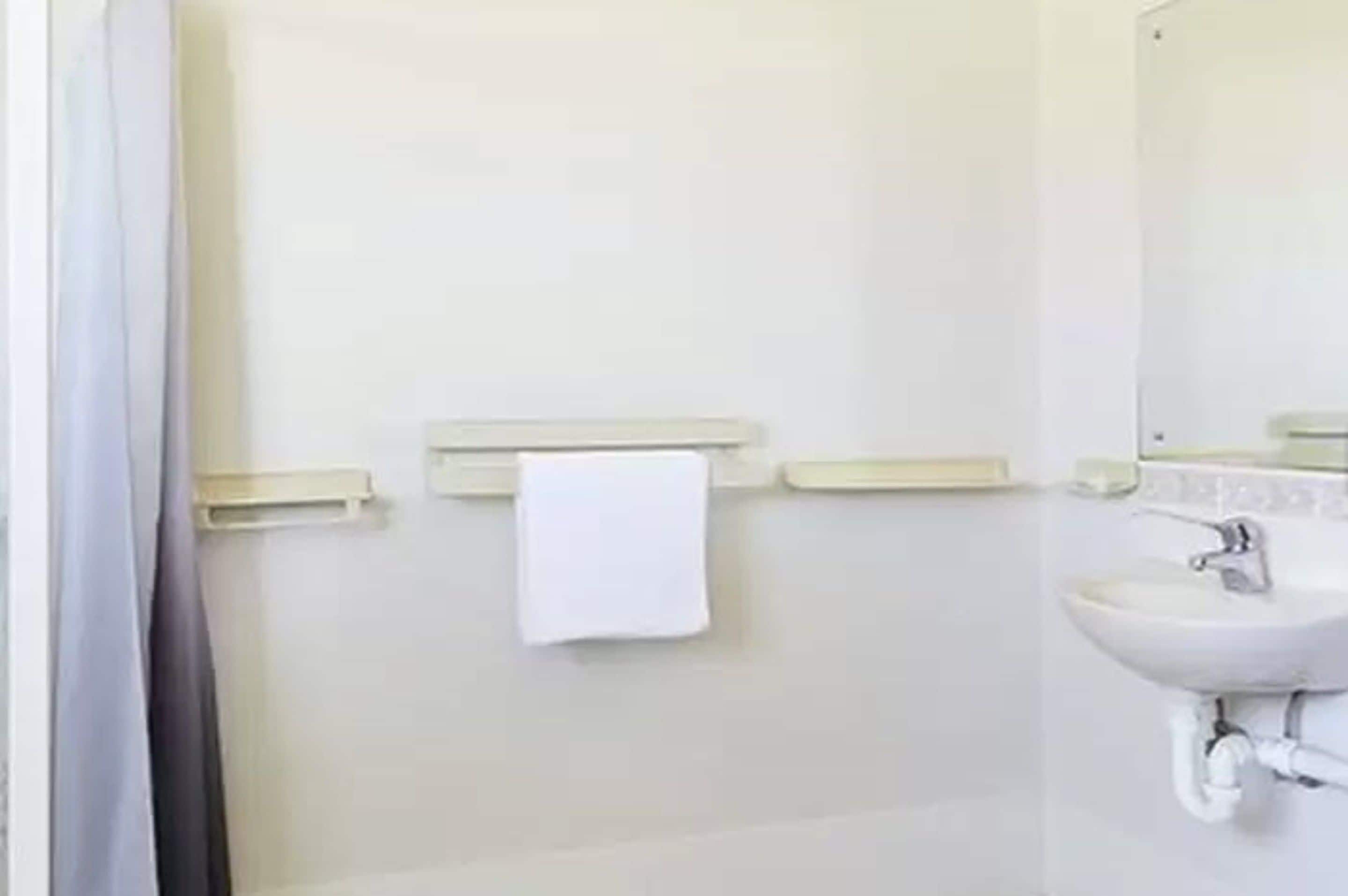 Een badkamer met een wit wastafel, een spiegel en een handdoek aan de muur.