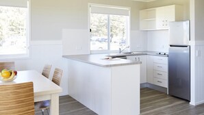 Una cucina moderna con mobili bianchi, un'isola centrale e un frigorifero integrato.