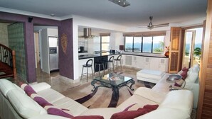 Una sala de estar moderna con un sofá, una mesa de centro de vidrio y vistas a la cocina.
