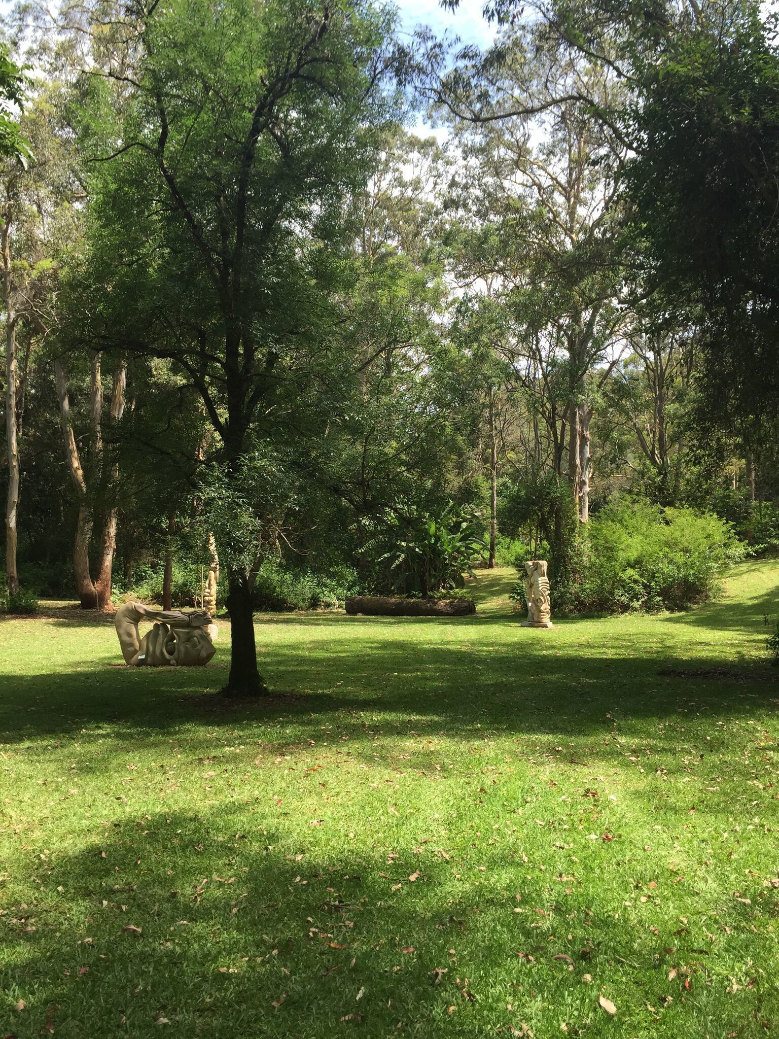 A park with a sculpture, trees, and a grassy area.