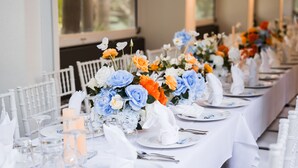 A long table set for a formal event with white chairs, glassware, and floral centerpieces. - Songbirds Rainforest Retreat (Tamborine Mountain)
