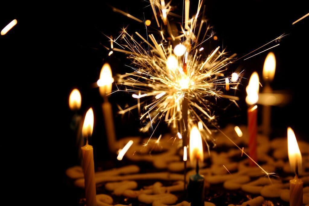 A close-up of a sparkler with multiple candles in the background.