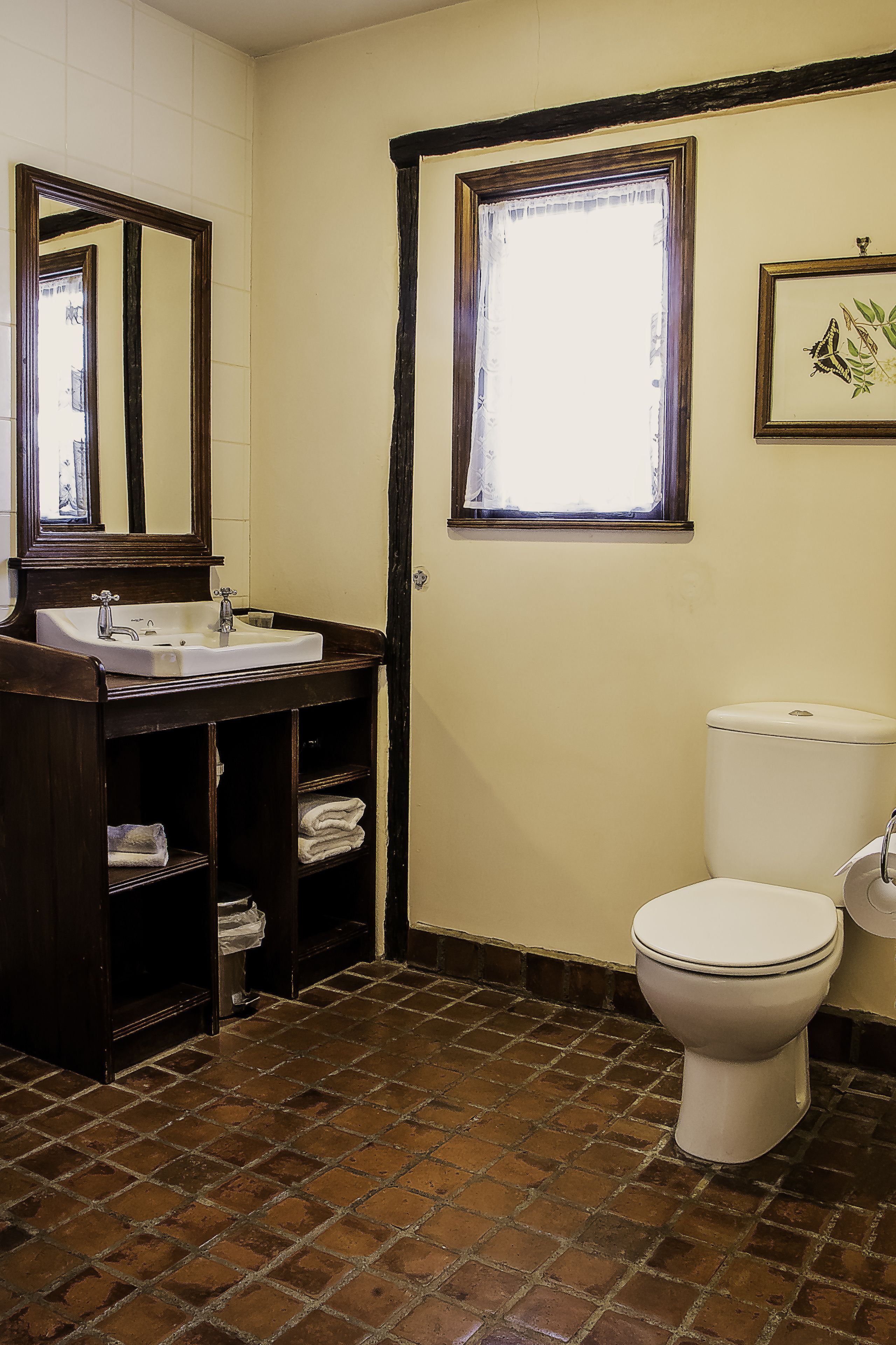 Un baño con lavamanos, espejo, inodoro y ventana.