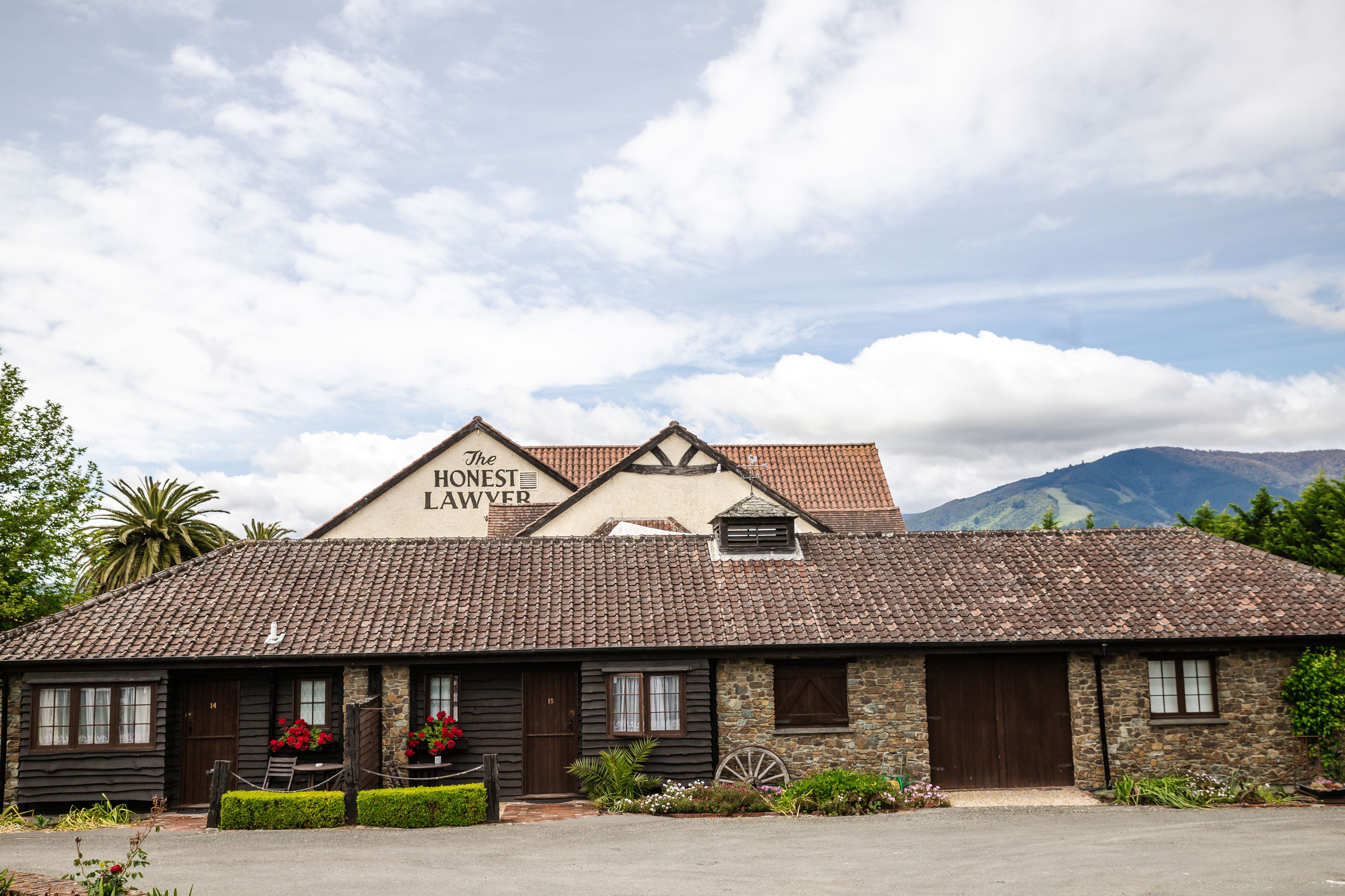 A traditional building with a sign reading "The Honest Lawyer." It features a stone facade, wooden doors, and a tiled roof.