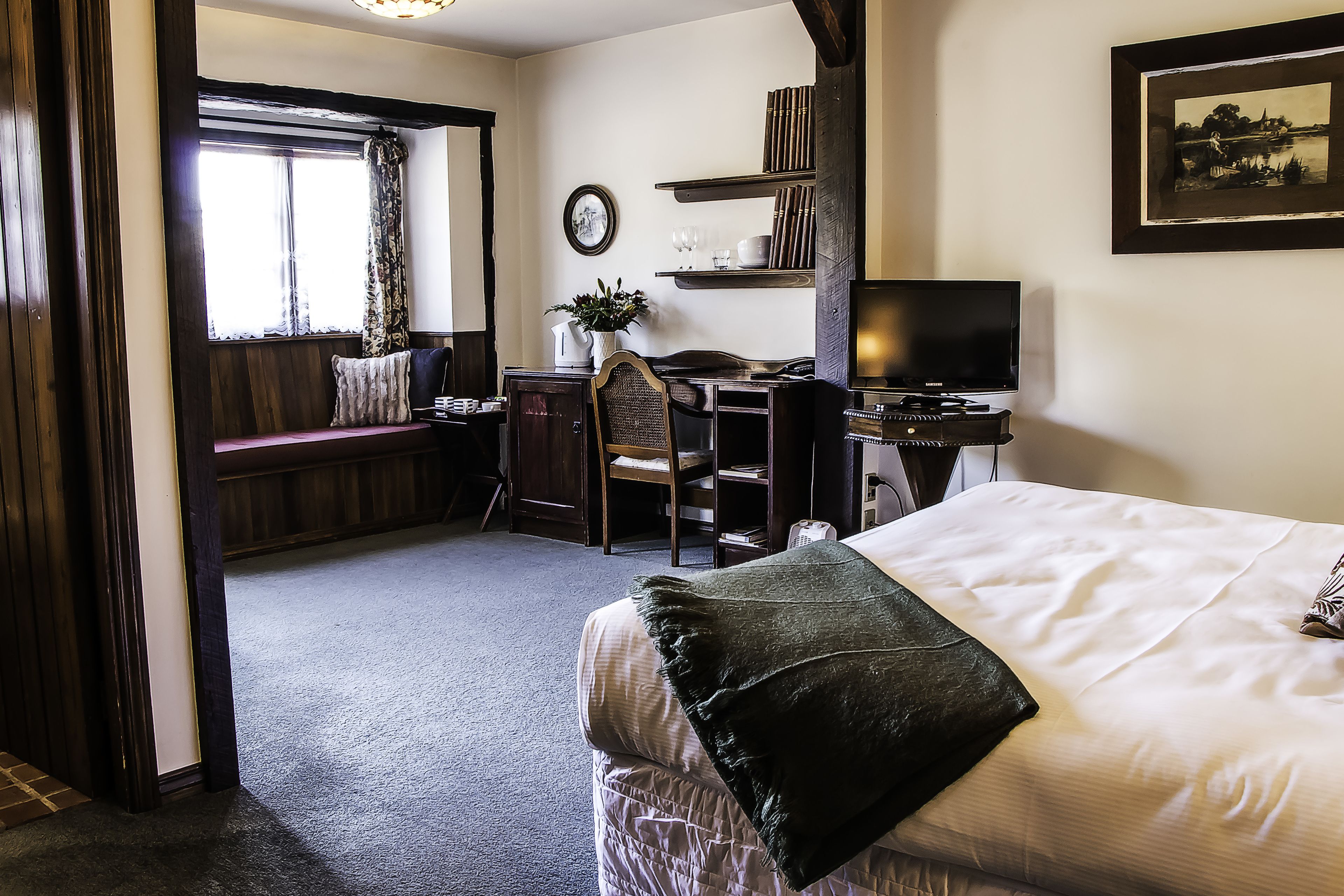 A hotel room with a bed, a desk, a chair, a television, and a window with curtains.