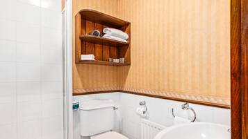Ein Badezimmer mit Toilette, Waschbecken und einem Holzregal mit Handtüchern.