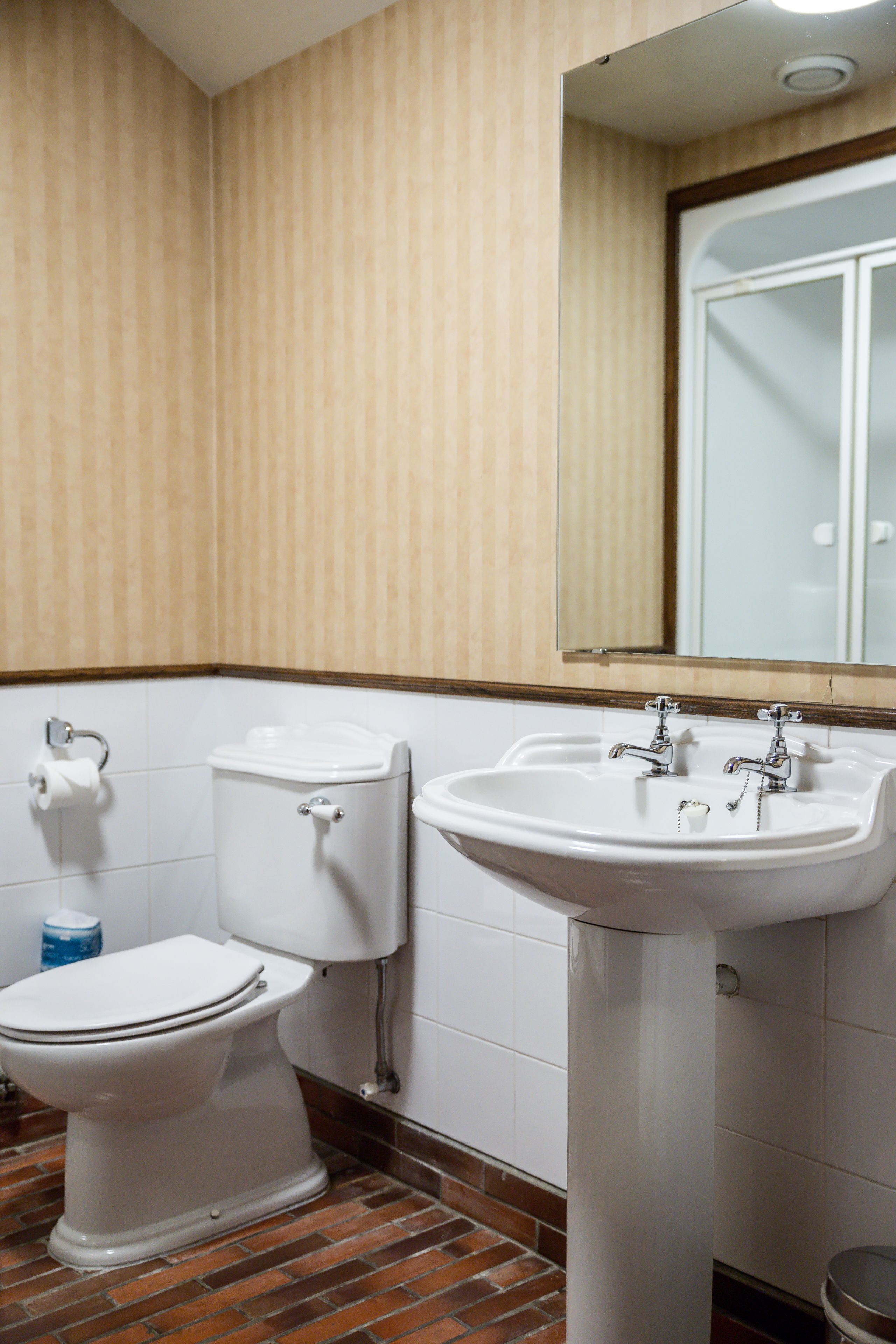 Een badkamer met toilet, wastafel en spiegel.
