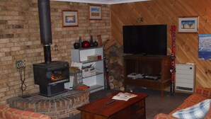Una sala de estar acogedora con chimenea de ladrillo, un televisor y muebles con estampado de cuadros.