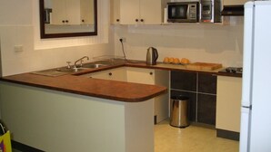 Una cocina compacta con lavamanos, microondas y un refrigerador pequeño.