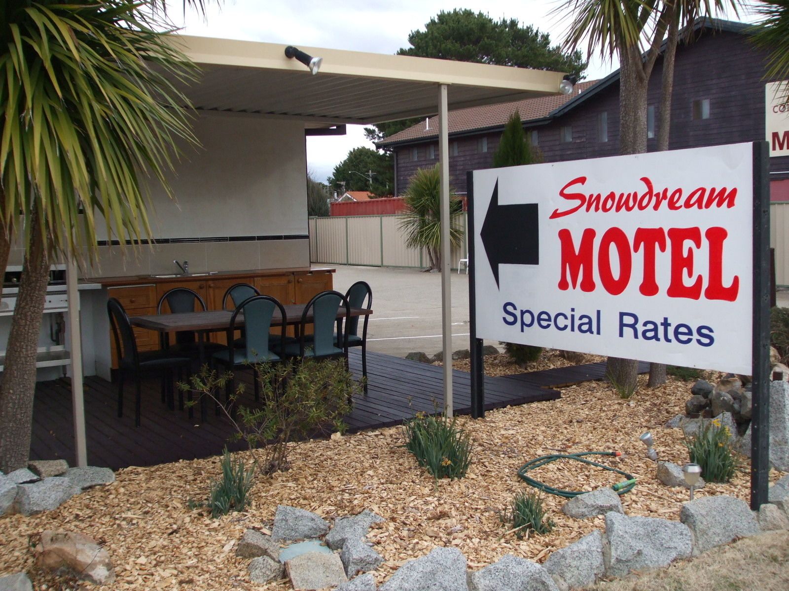 A motel sign with a directional arrow, outdoor seating, and a covered patio area.